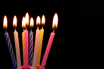 Birthday candles burning and melting on black background. Copy space for text.