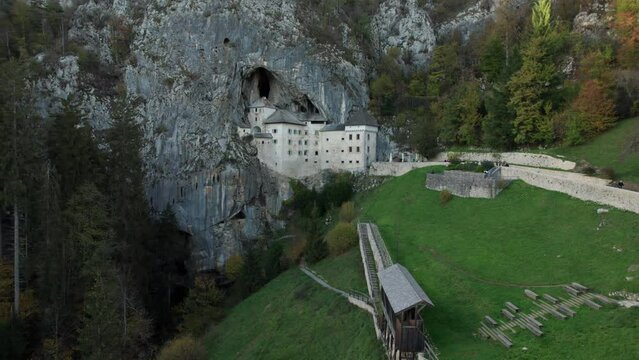 aerial slow motion shot with forward move-in on Predjama Castle at sunset