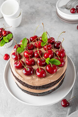 Naked Black forest cake, Schwarzwald pie. Cake with dark chocolate, cream and cherry on a gray concrete background. Copy space