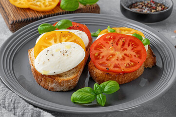 Sandwich caprese with rye bread, tomatoes, mozzarella and fresh basil on a gray plate on a concrete background. Healthy food.