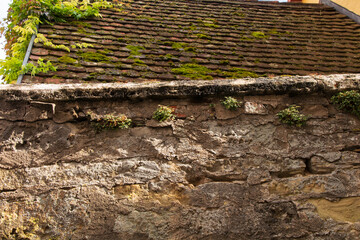Restored city wall that is a few hundred years old and a house roof with moss