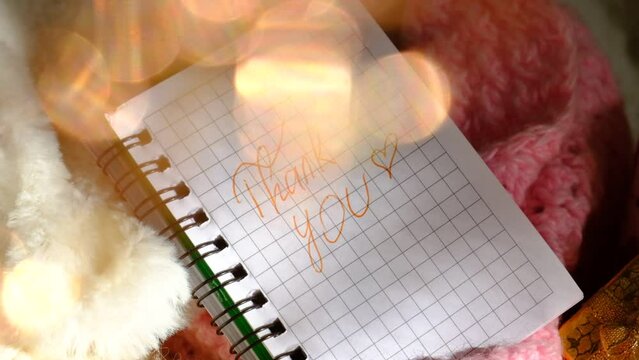 A golden gift box and shiny golden sparkles bokeh. Text Thank You on paper, notepad. Wedding, Birthday, Valentines Day, dating.