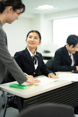 教師と教室で勉強している制服の高校生