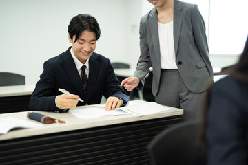 教師と教室で勉強している制服の高校生