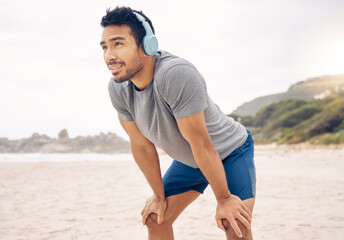 Fitness, headphones and portrait of man on beach running for race, marathon or competition training. Sports, workout and young male athlete listen to music, radio or playlist for exercise by ocean.
