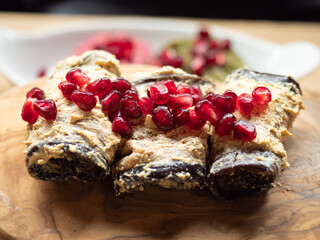 A delicious vegan plate: Aubergine rolls with humus and a topping of pomegranat seeds