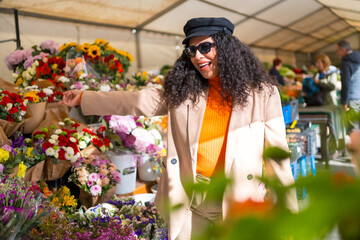 Happy latin woman choosing flowers in an outdoor flower shop