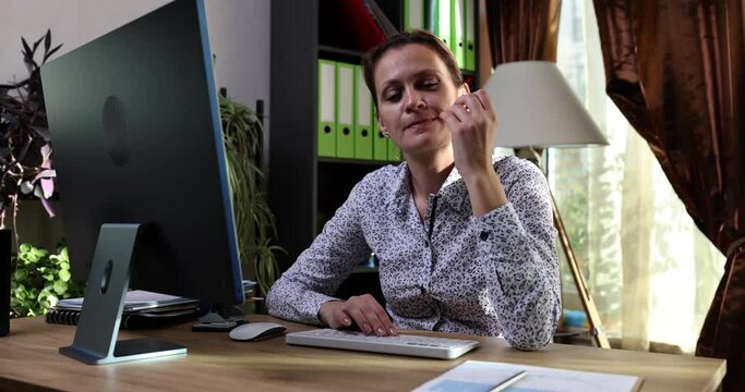 Nervous businesswoman in office biting nails and working on computer. Nail biting onychophagia causes symptoms