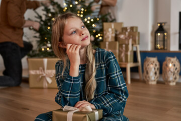 Thoughtful caucasian girl holding a Christmas present and looking away