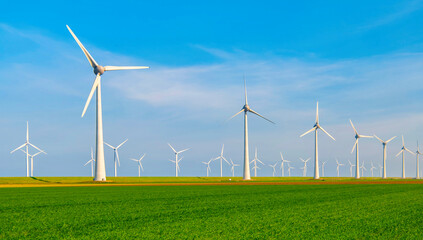 Fototapeta premium Windmill park with windmill turbines in the Netherlands, green energy with a green agriculture field of grass in the foreground, Energy transition clean energy concept