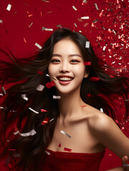 Cute and happy asian woman portrait on dark red background with confetti in the air