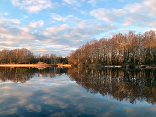 golden hour, wonderful autumn landscape by the river, beautiful reflection of the sky and forest in the water