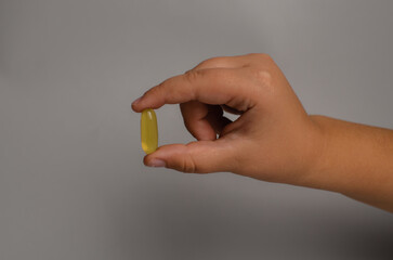 Child hands holding fish oil capsules on white background. Children's health care concept.