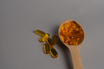 Omega 3 capsules in the wooden spoon.Cod liver oil capsules on the table. Healthy life style concept