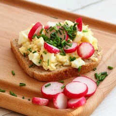 Fototapeta na wymiar Egg salad over whole grain toast with radish and chives. Homemade spread made from eggs and processed cheese on white table.