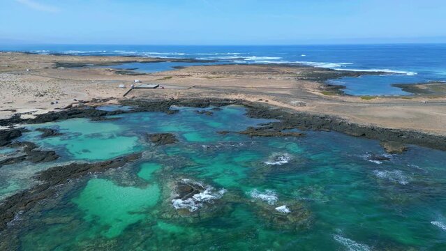 Aerial fly up orbital clip of the natural pools and volcanic rock formations near El Cotillo in Fuerteventura Spain