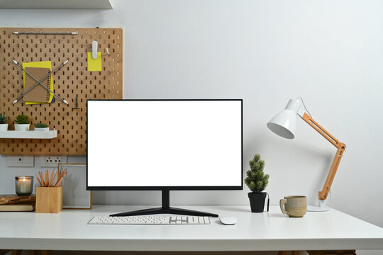 Creative workspace with blank computer desktop, lamp and stationery