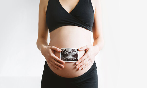Pregnant woman holding ultrasound baby image. Pregnant belly and sonogram photo