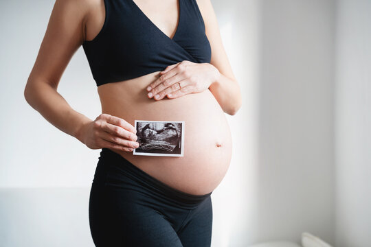 Pregnant woman holding ultrasound baby image. Pregnant belly and sonogram photo