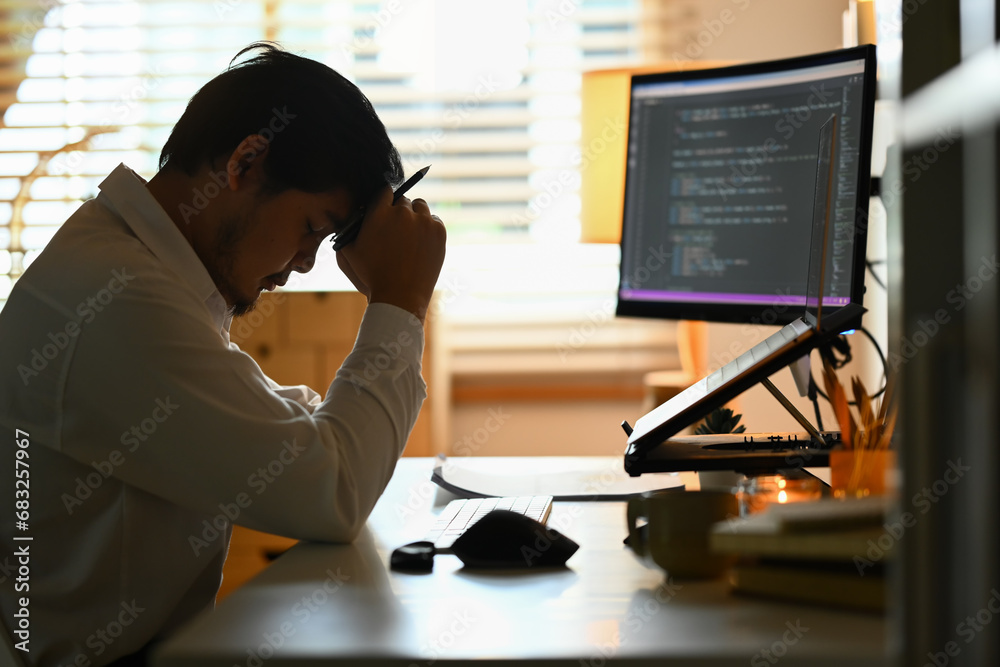 Wall mural male programmer looking stressed out while working on difficult project at workplace