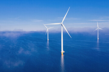 Offshore windmill park with fog and clouds and a blue sky, windmill park in the ocean aerial view...