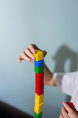 Hand of a teenage girl making a tower with colored wooden blocks in therapy session. Therapy and mental health concept