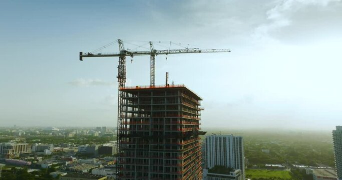 Aerial view of new developing residence in American urban area. Tower cranes at industrial construction site in Miami, Florida. Concept of housing growth in the USA