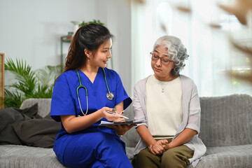 Female practitioner nurse explaining medicine dosage to elderly woman during home visit. Health...