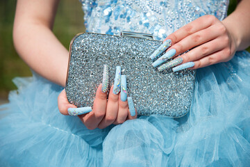 Close-up of a woman wearing a formal light blue dress, her hands with an attractive manicure and...