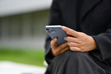 Cropped shot of businesswoman using mobile phone chatting online with friends during break