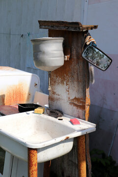 Homemade Corner For Washing Hands And Dishes In The Garden Of A Village House - An Old Metal Washbasin And Sink With Sponges, A Mirror And Brushes For The Summer Season In Russia. Vertical Photo