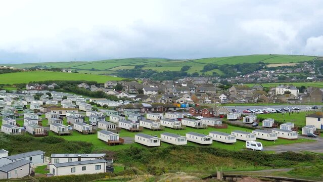 High angle panning shot of caravan park or trailer camp in coastal village of St. Bees at low tide of Irish Sea.
