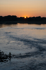 Naklejka premium Lone fisherman on bank of Loire river fishes at sunset at dusk, France