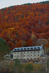 The Parador de Bielsa with the red, ocher, yellow and green colors of autumn in the beech forests of the Pyrenees of the Pineta Valley, in the Ordesa and Monte Perdido National Park. Huesca. Aragon. S
