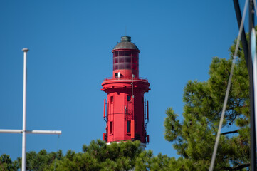 View on red lighthouse Le Phare du Cap Ferret, Arcachon Bay with many fisherman's boats and oysters farms near , Cap Ferret peninsula, France, southwest of Bordeaux, France's Atlantic coastline - obrazy, fototapety, plakaty