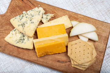 English cheeses collection, mature and coloured cheddar cheese and semi-soft, crumbly old stilton...