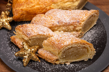 Christmas dessert, fresh baked Dutch filled spicy cookies from puff pastry with almonds on black board close up