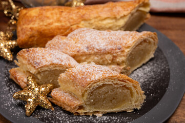 Christmas dessert, fresh baked Dutch filled spicy cookies from puff pastry with almonds on black board close up