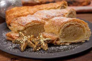 Christmas dessert, fresh baked Dutch filled spicy cookies from puff pastry with almonds on black board close up