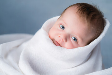 lovely baby wrapped in white towels smiling at camera. advertisement space.blue eyes