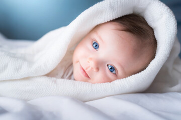 lovely baby wrapped in white towels smiling at camera. advertisement space.blue eyes