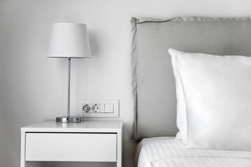 Minimalist Bedroom Concept: White Bedding, Pillow, and Bedside Table with Lamp.  Perfect for use in home decor publications, interior design concepts, and lifestyle promotions.