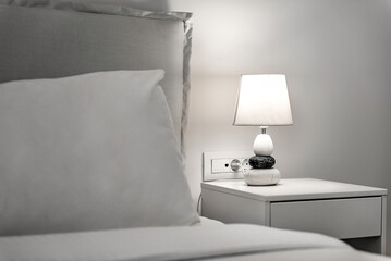 Minimalist Bedroom Concept: White Bedding, Pillow, and Bedside Table with Lamp.  Perfect for use in home decor publications, interior design concepts, and lifestyle promotions.