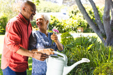 Happy diverse senior couple gardening in sunny garden