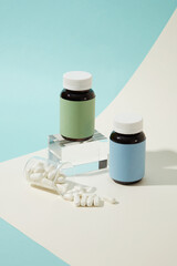 White pills were poured from a transparent laboratory beaker. Two medicine bottles without label are displayed on a table with a glass podium. Drug advertising model.