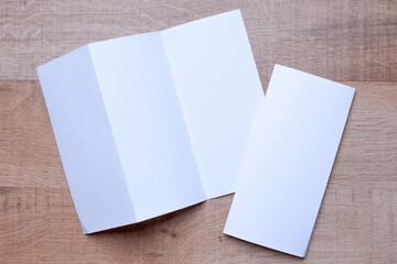 Blank trifold brochure A4 booklet on wooden background with clipping path. Folded and unfolded.
