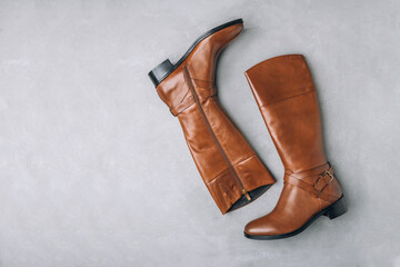 Boots. Women's brown leather high long boots on gray background. Top view.