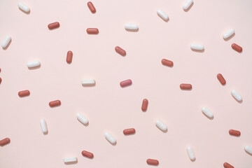 View from above of white and red tablets randomly arranged on a pastel background. Tablets are the most commonly used medicine, the medicine is divided into precise doses for each tablet.