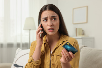 Confused woman with credit card talking on phone at home. Be careful - fraud