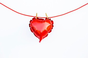 little foil red hart shaped baloon on a clothespins on red rope isolated on white background. love,...